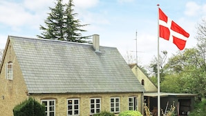 A traditional house with a sloped roof, a flagpole with a flag, and a well-maintained garden. - 6 Person Holiday Home in Aeroskobing (Aeroskobing)