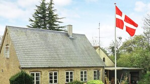 A traditional brick house with a sloped roof, a flagpole with a flag, and well-maintained hedges. - 6 Person Holiday Home in Aeroskobing (Aeroskobing)