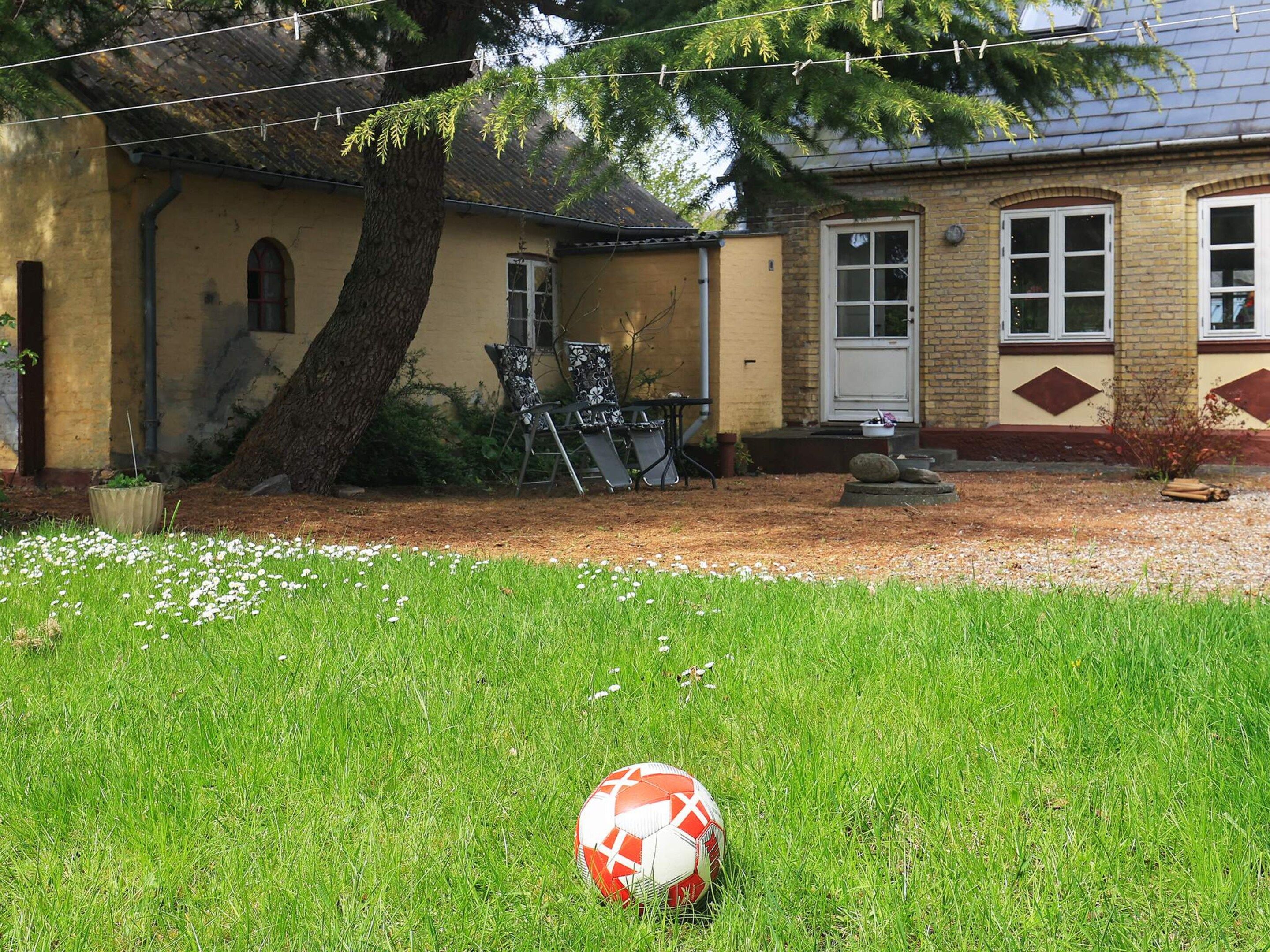 A residential property with a lawn, a patio area, and a house with a brick facade.