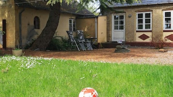 A residential property with a lawn, a patio area, and a house with a brick facade.