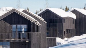 Een rij houten hutten met sneeuw bedekte daken en een heldere lucht.