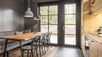 A modern kitchen with a wooden dining table, chairs, and pendant lights.