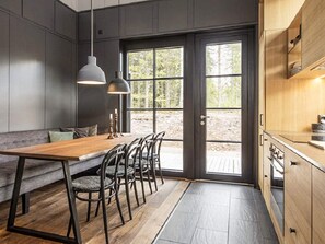 Una cocina moderna con una mesa de comedor de madera, sillas y lámparas colgantes.