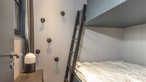 A bunk bed room with a ladder leaning against the wall, a small wooden cabinet, and a door with circular handles. - 4 Star Holiday Home in Salen (Salen)