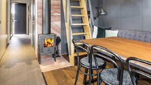 Een modern interieur met een houten eettafel, zwarte stoelen, een open haard, een ladder en een bank.