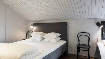 A bedroom with a bed, a chair, and a wall-mounted lamp.