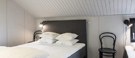 Een slaapkamer met een bed, een stoel en een wandlamp.