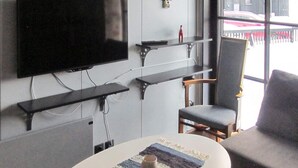 Un salon moderne avec un téléviseur à écran plat fixé au mur, une table basse avec un tapis et deux fauteuils.