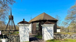 A church with a steeple, a stone wall, and a gravel path leading to the entrance.