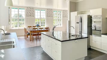 A modern kitchen with white cabinetry, a central island, and a dining area with wooden chairs and a table.