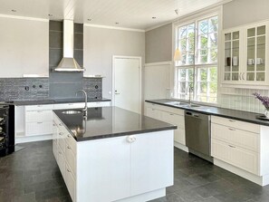 A modern kitchen with a central island, white cabinetry, a black countertop, and a window with a view of greenery. - 4 Star Holiday Home in Morlunda (Mörlunda)