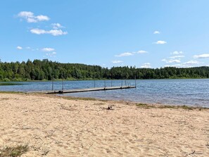 A sandy beach with a wooden dock extending into a calm lake, surrounded by dense forest. - 4 Star Holiday Home in Morlunda (Mörlunda)
