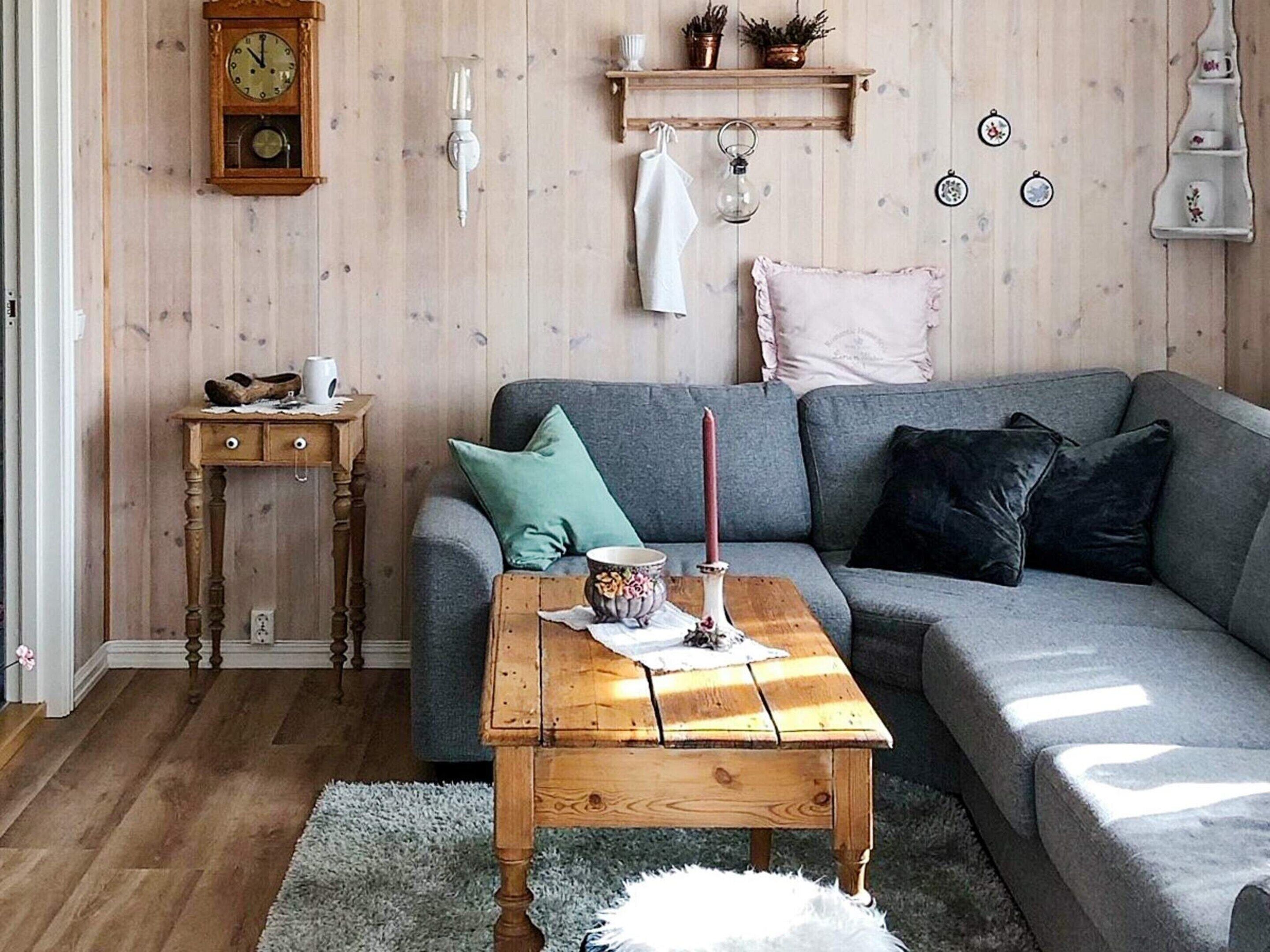 A cozy living room with a grey sofa, a wooden coffee table, and a small side table.