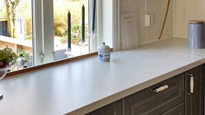 Una cucina con un piano di lavoro bianco, mobili scuri e una finestra vista all'esterno.