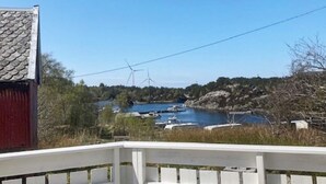 Paesaggio costiero con turbine eoliche, imbarcazioni e un edificio in legno.