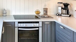Una cucina con forno a incasso, macchina da caffè e teiera decorativa sul piano di lavoro.