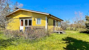 Una casa gialla con un portico, immersa nel verde tra l'erba e gli alberi.