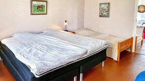 A bedroom with a double bed, a nightstand, a lamp, and two framed pictures on the wall. - 6 Person Holiday Home in Borgholm (Borgholm)