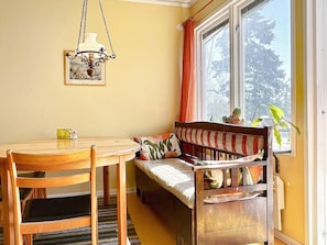 A dining area with a wooden table and chairs, a bench with cushions, a hanging light fixture, and a window with curtains. - 6 Person Holiday Home in Borgholm (Borgholm)