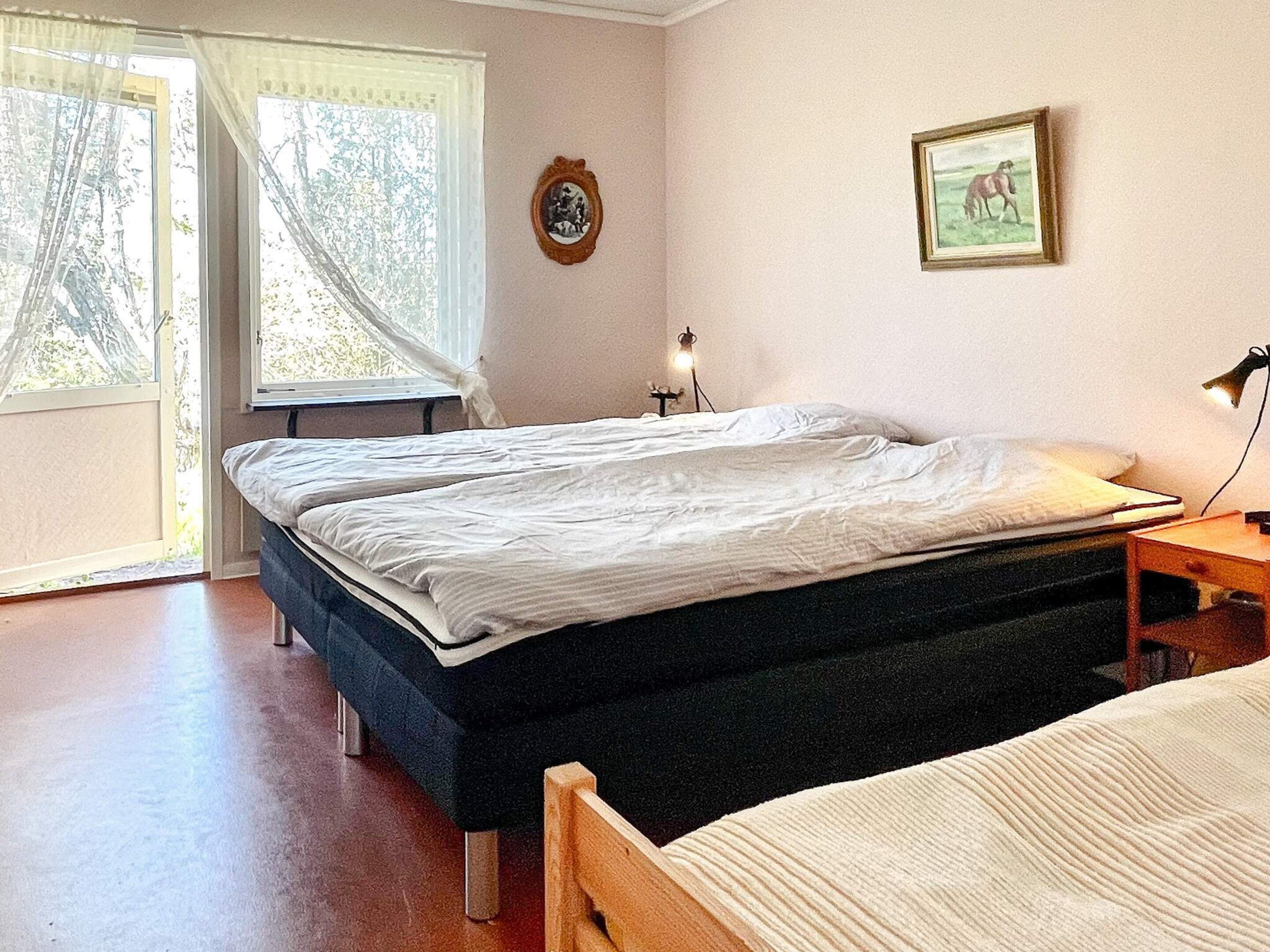 A bedroom with a bed, a bedside table, a lamp, and a window with curtains.