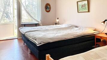 A bedroom with a bed, a bedside table, a lamp, and a window with curtains.