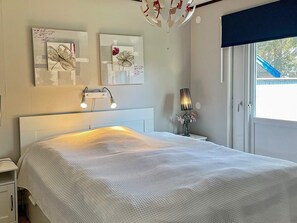 A bedroom with a bed, bedside lamps, a nightstand, a wall-mounted lamp, and artwork. - 8 Person Holiday Home in Monsteras (Monsteras)
