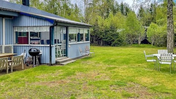 A blue house with a deck, a barbecue grill, and outdoor seating.