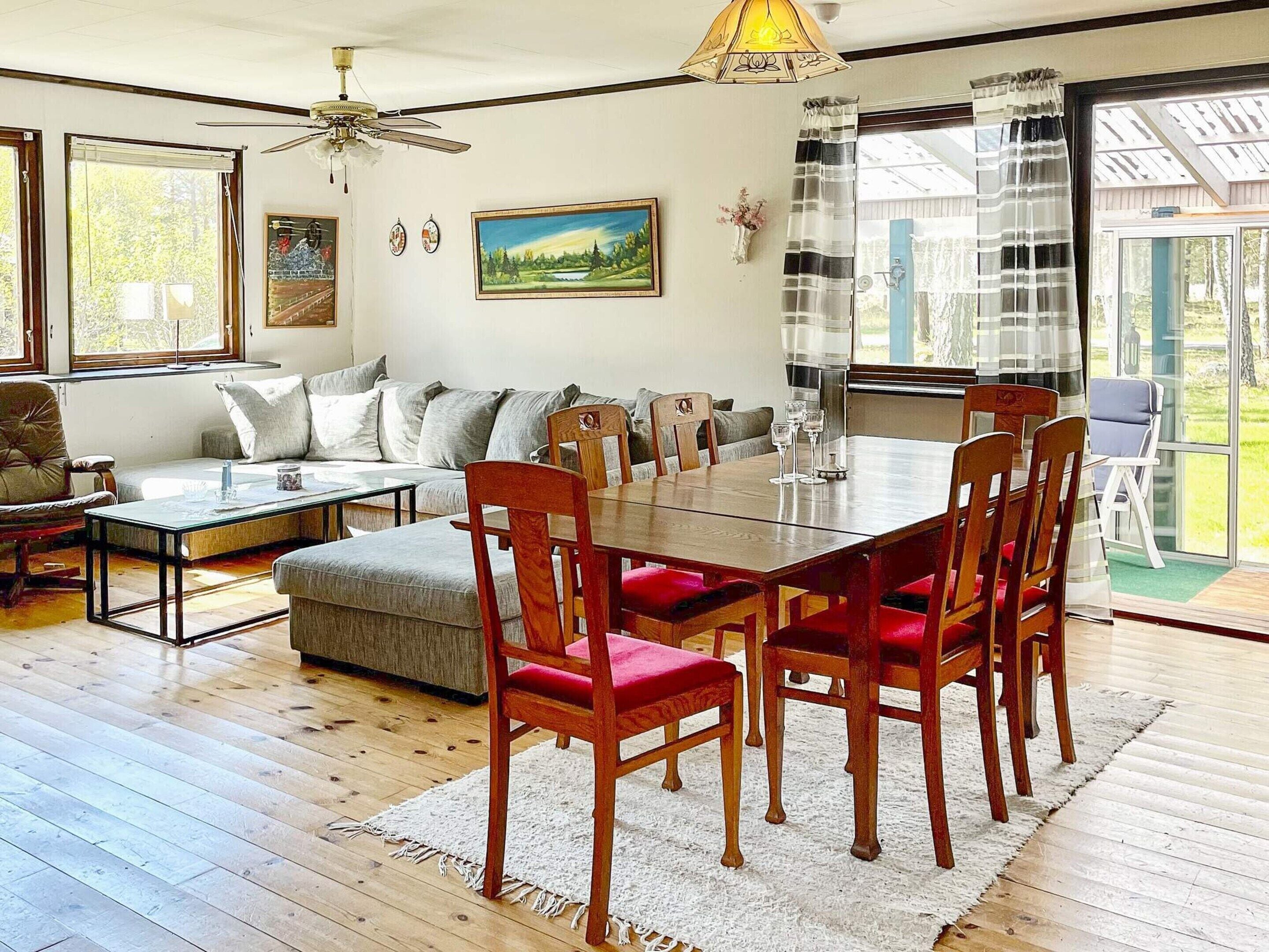 A spacious living room with a dining table, chairs, a sofa, and a ceiling fan.