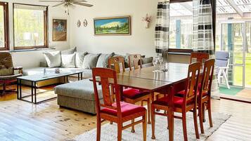 A spacious living room with a dining table, chairs, a sofa, and a ceiling fan.