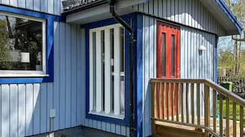 A building with a blue and white exterior, a red door, and a wooden deck.