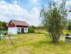 A red and white barn with a door and windows, surrounded by a grassy yard and a tree. - 3 Person Holiday Home in Berga (Berga)