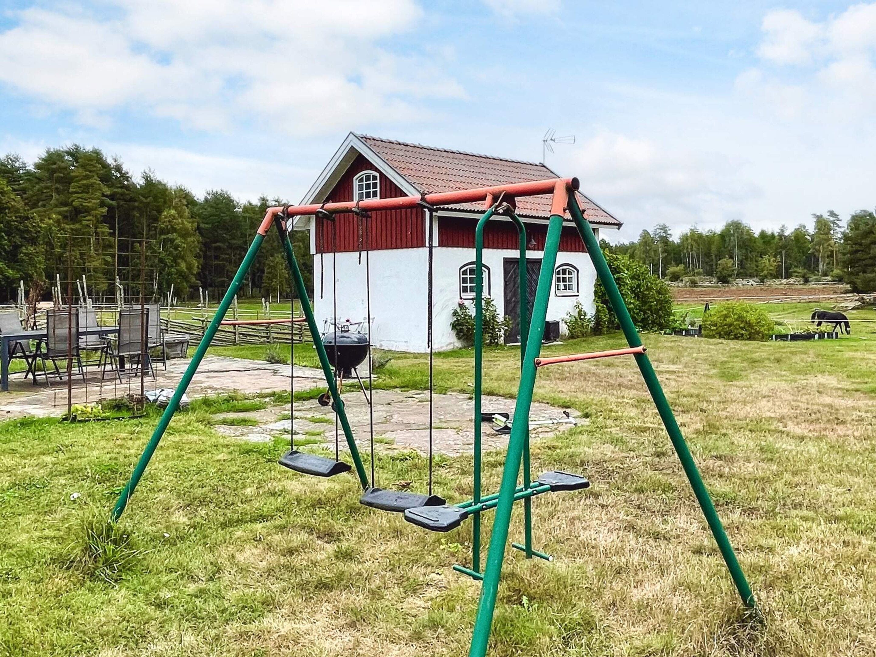 Una casa con un columpio en un área verde.