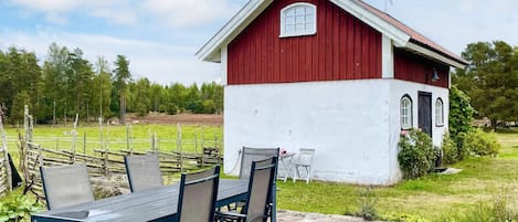 A red and white building with a small porch and a table with chairs in front.