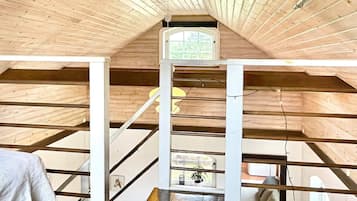 Un dormitorio en el ático con vigas de madera, un tragaluz y una escalera.