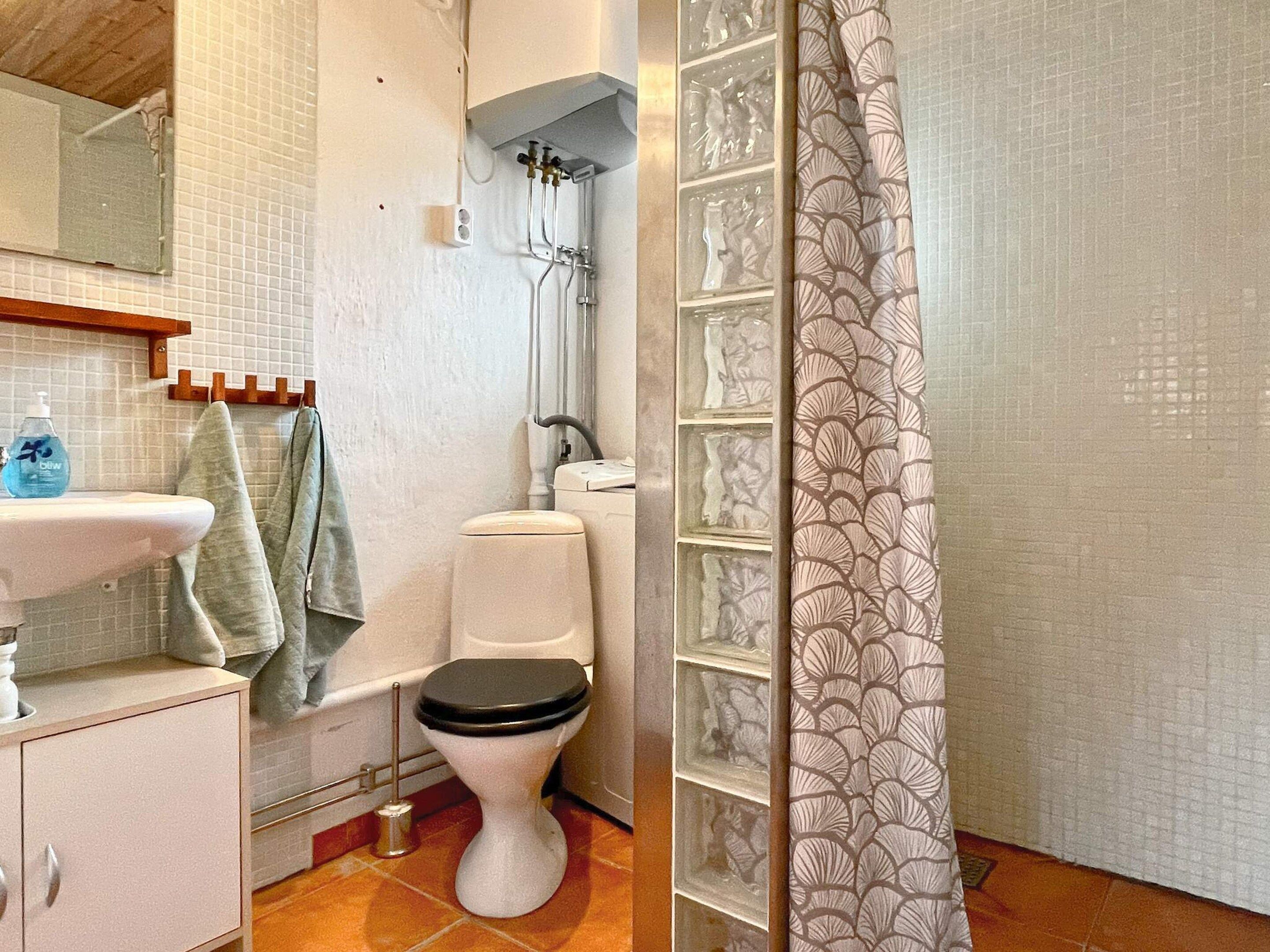 A bathroom with a white sink, a toilet, a shower, and a patterned shower curtain.