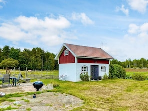 A small red and white house with a red roof, a black grill, and a stone patio. - 3 Person Holiday Home in Berga (Berga)