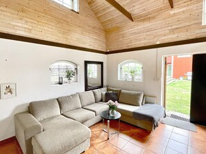 A cozy living room with a sectional sofa, a small round table with a vase, and two windows with plants. - 3 Person Holiday Home in Berga (Berga)