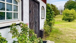 Una casa con fachada blanca, una puerta de madera oscura y una ventana con marco blanco.