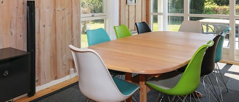 A wooden-paneled room with a large table and chairs, a black cabinet, and a window with a view of greenery.