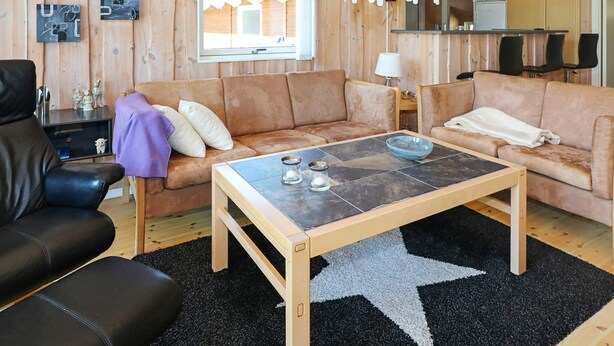 A cozy living room with a wooden ceiling, a star-patterned rug, two sofas, a coffee table, and a television. - 8 Person Holiday Home in Hadsund (Hadsund)