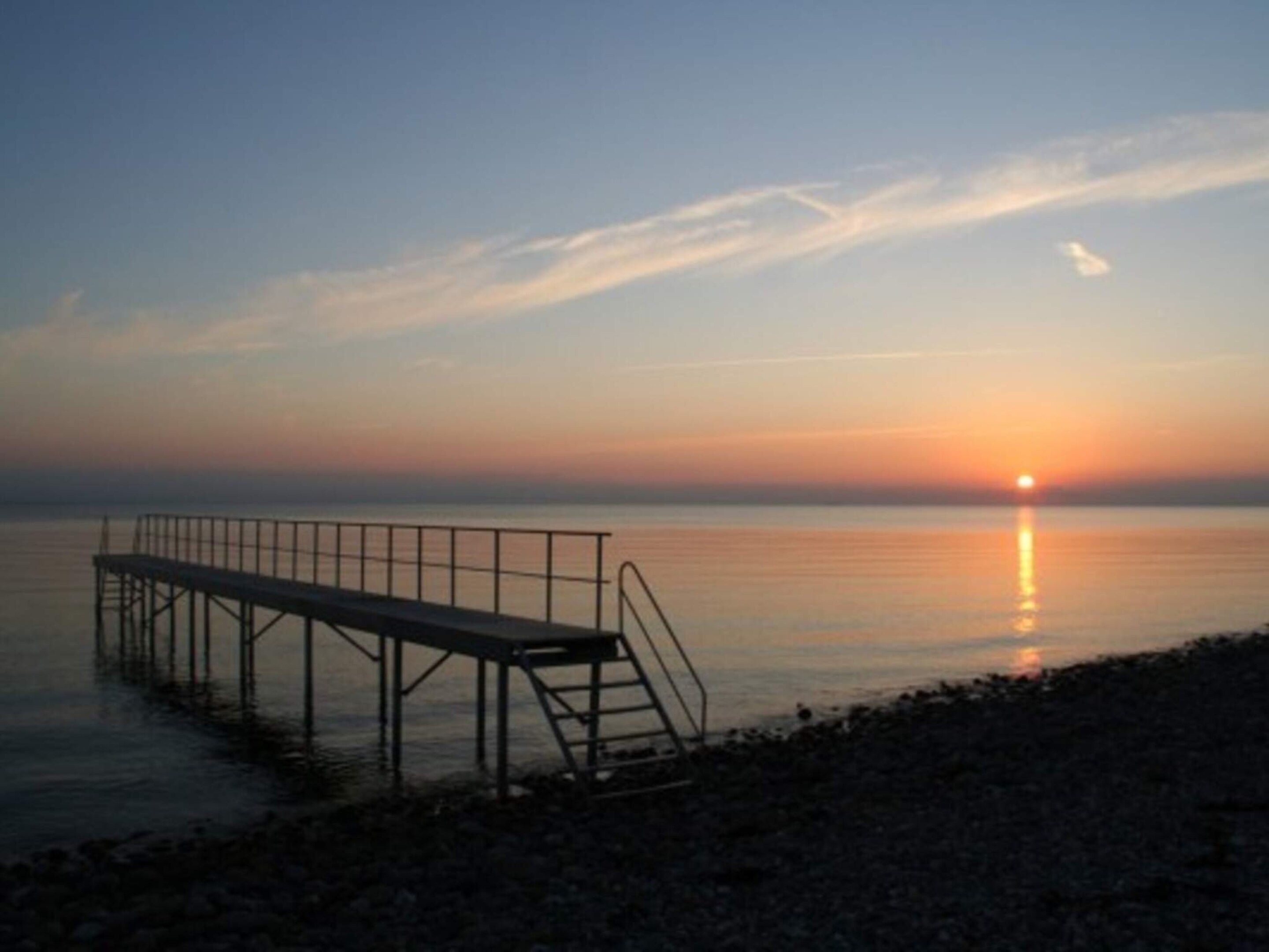 A pier extending into calm waters at sunset.