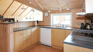 A kitchen with wooden cabinets, a dishwasher, a sink, and a window. - 8 Person Holiday Home in Hadsund (Hadsund)