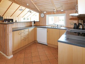 A kitchen with wooden cabinets, a dishwasher, a sink, and a window. - 8 Person Holiday Home in Hadsund (Hadsund)