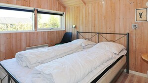 A room with wooden walls, a bed with white bedding, a chair, and a window. - 8 Person Holiday Home in Hadsund (Hadsund)