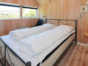 A room with wooden walls, a bed with white bedding, a chair, and a window. - 8 Person Holiday Home in Hadsund (Hadsund)