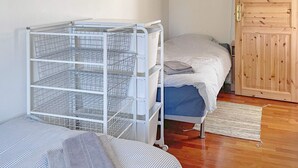 A room with a metal storage unit, two beds with striped bedding, a wooden door, and a woven rug on the floor. - 4 Star Holiday Home in Granna (Gränna)