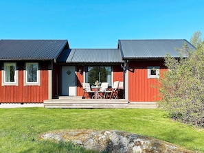 A two-story building with a red exterior and a grey roof, featuring a front porch with outdoor seating. - 4 Star Holiday Home in Granna (Gränna)