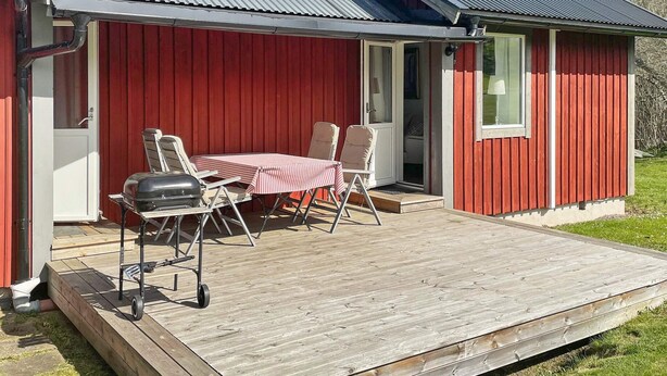 A red wooden building with a covered patio, a grill, and outdoor seating. - 4 Star Holiday Home in Granna (Gränna)