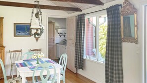 A dining area with a table set for two, chairs, a hanging light fixture, and a view of the kitchen through an open door. - 4 Star Holiday Home in Granna (Gränna)