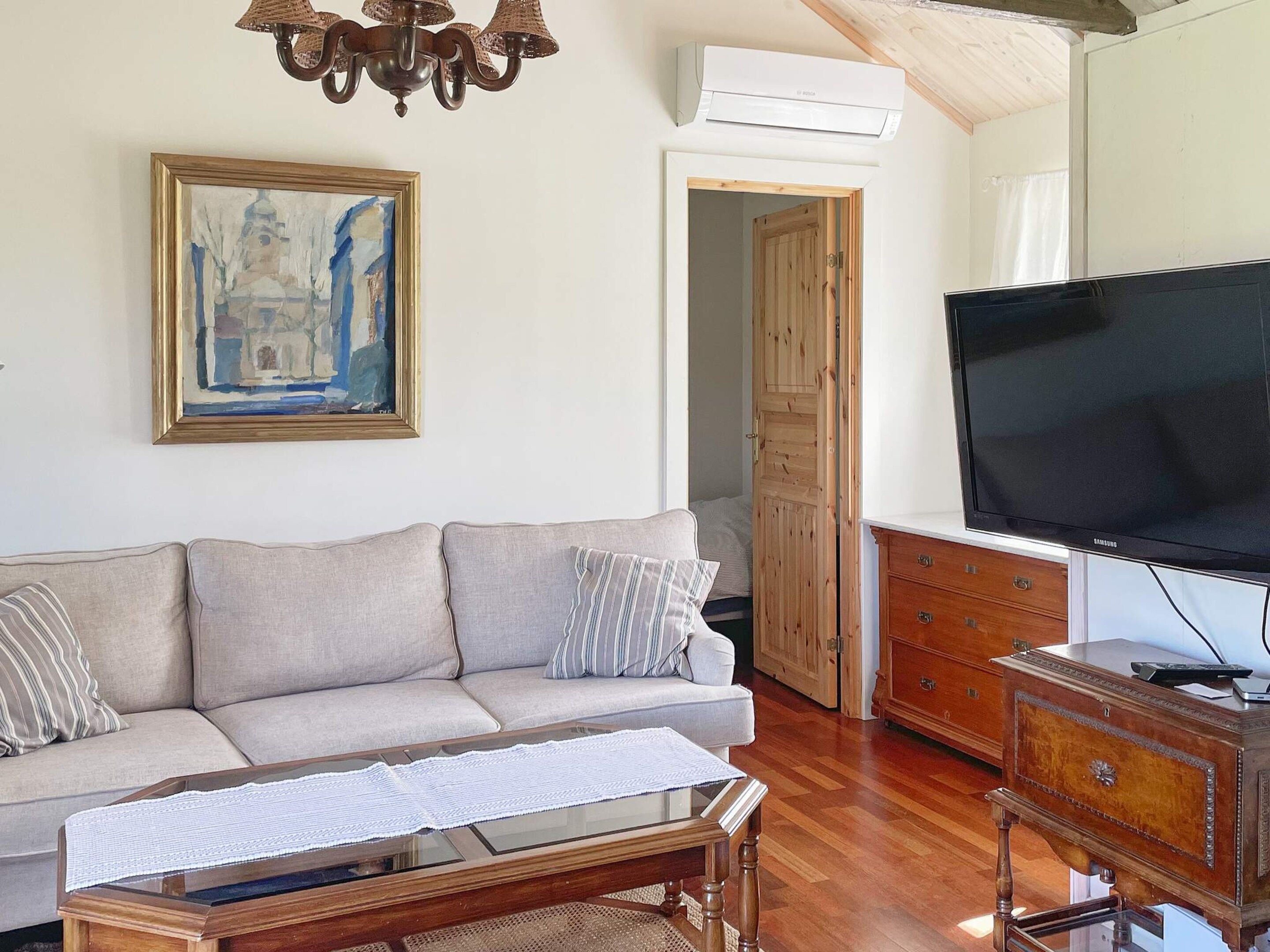 Un salon avec un canapé, un téléviseur, un meuble en bois et un tableau accroché au mur.